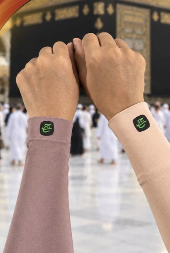 Dua tangan memakai handsock berlogo travel di hadapan Kaabah